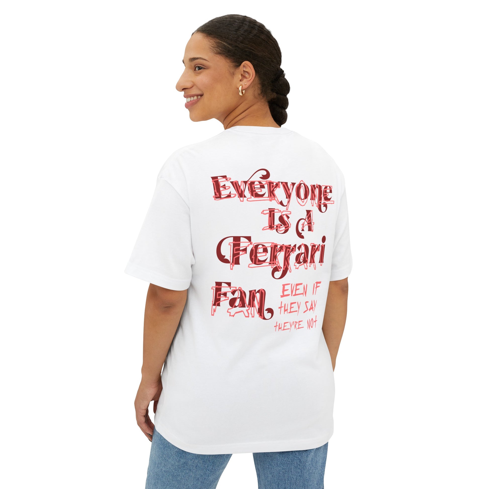 Rear view of white oversized T-shirt of Forza Ferrari. The t-shirt reads Sebastian Vettel's words - Everyone is a Ferrari fan, even if they say they're not. The t-shirt is made from French Terry cotton. Forza Ferrari is the most popular celebration chant among Tifosi and Scuderia Ferrari drivers alike. A female model is wearing the t-shirt so that back of the t-shirt is visible.